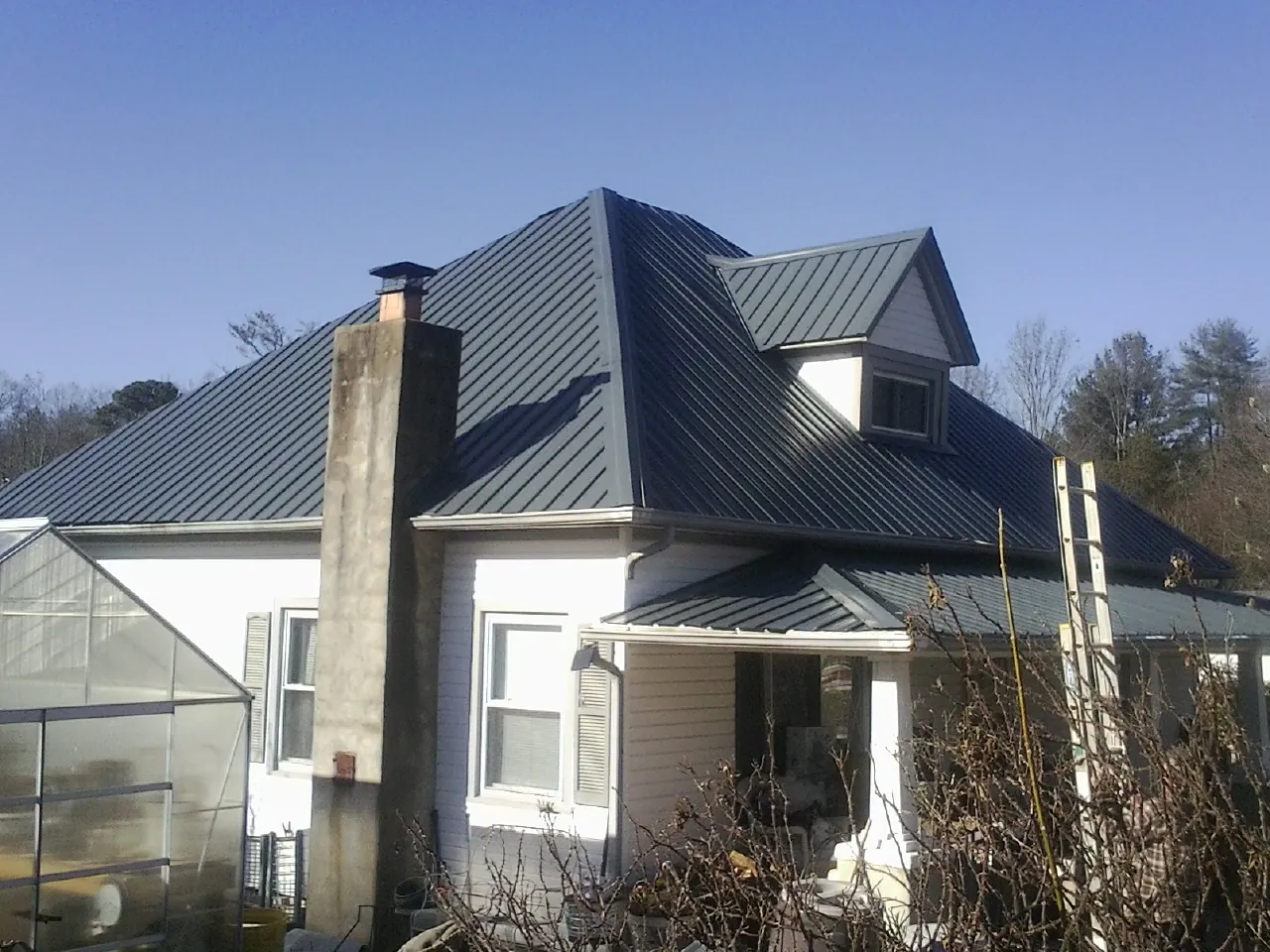 Dark blue standing seam metal roof on a white farmhouse with dormer — Slate & Tile Roof Repair by Roofing Brothers in Cressona
