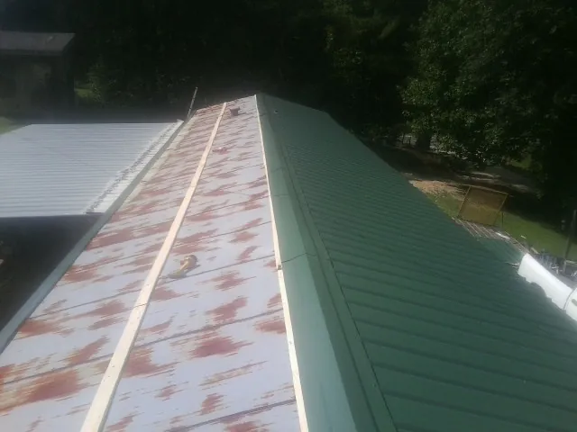 Old rusted panels beside newly installed green metal roofing — Wind Damage Roof Repair by Roofing Brothers in Cressona