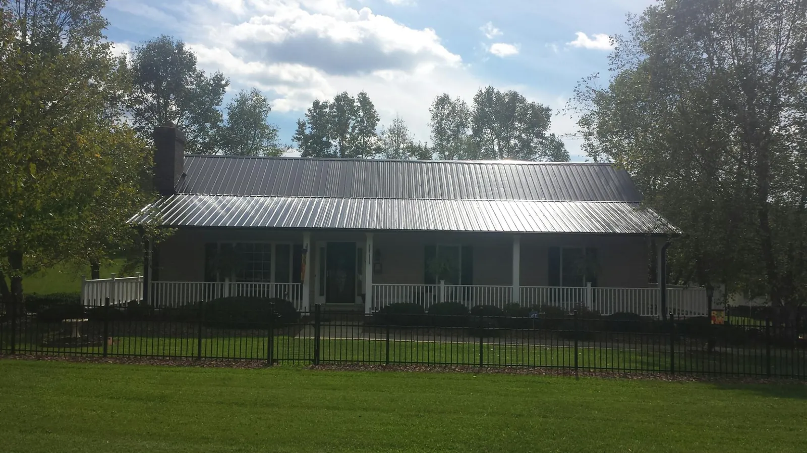 Gray metal roof on a brick ranch with a full width front porch — Gutter Guard Installation work by our crew in Cressona