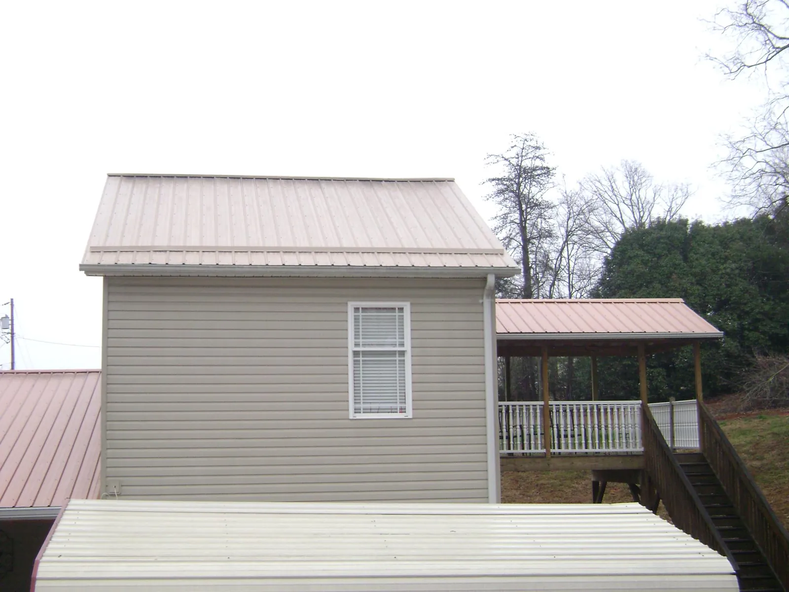 Tan metal roofs on a two story addition and attached porch, from a Roof Replacement job in Cressona