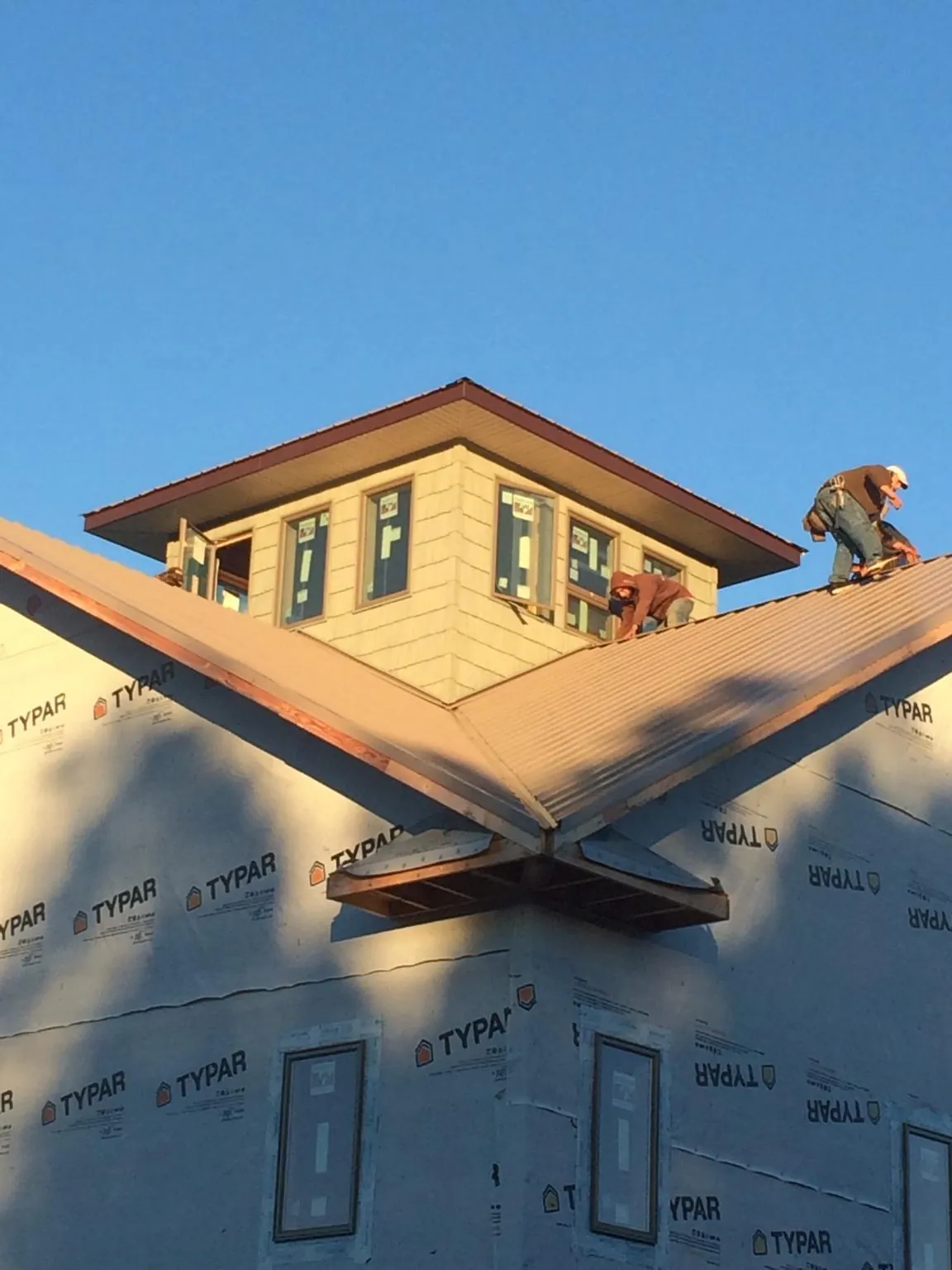 Roofers working around a rooftop cupola on a new metal roof at sunset — Roof Waterproofing in Cressona by Roofing Brothers